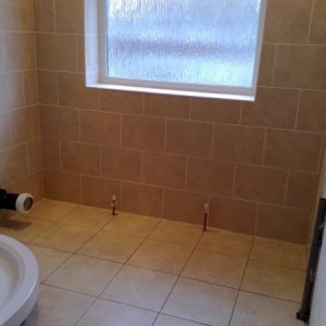 Ashford - Tiled floor and walls in bathroom using 12x12 porcelain floor tiles and 12x10 tiles in a brick-bond formation