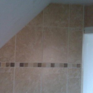 Wall tiling in sloping ceiling, traventine border.