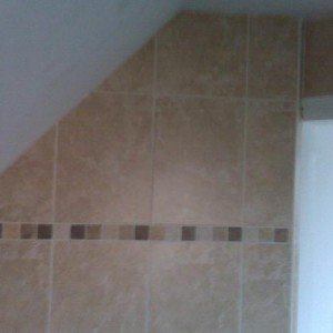 Wall tiling in sloping ceiling, traventine border.