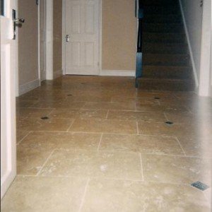 3) ENTRANCE HALLWAY - 600X400MM FILLED AND HONED MEDIUM TRAVERTINE WITH CAST METAL TACO INSETS.