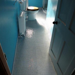 25mm white glass mosaic floor and skirting. Existing vinyl uplifted, existing floorboards made good secured and cupped areas flattened, then HBB fitted over before tiling.