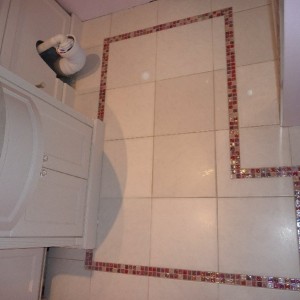 Small ensuit floor tiled in ceramic floor tiles with glass mosaics cut into the tile.