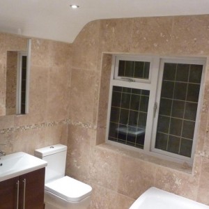 A beautiful bathroom fully tiles with filled and honed travertine on the walls and a porcelain floor.