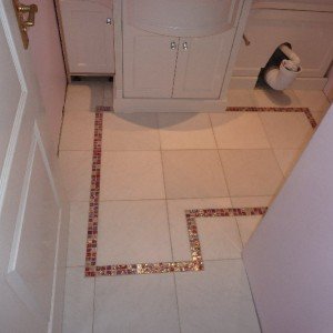 Pink glass mosaics cut into ceramic floor tiles.