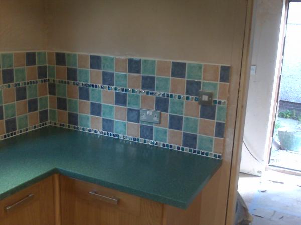 16k Oak Kitchen Installation with Silica(resin) worktops. Tiling with 100x100 ceramics with glass borders