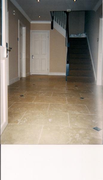 3) ENTRANCE HALLWAY - 600X400MM FILLED AND HONED MEDIUM TRAVERTINE WITH CAST METAL TACO INSETS.