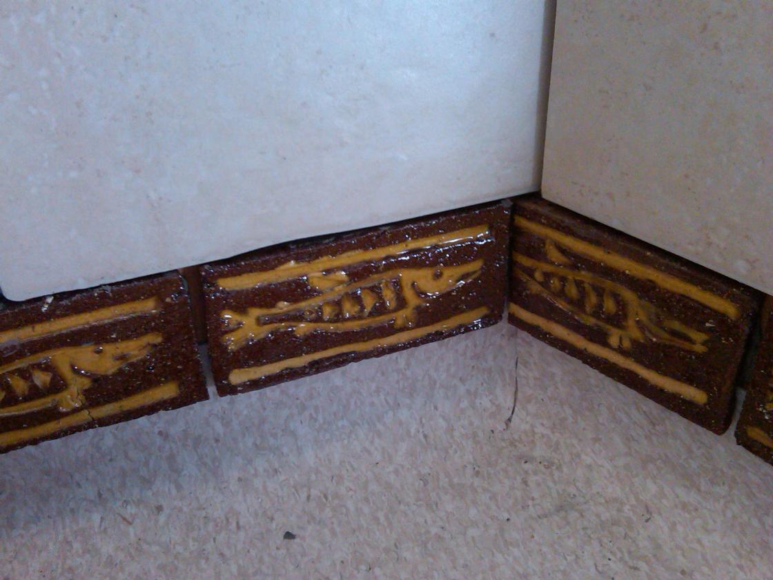 Hand made 'fish' tiles used as a skirting detail aboved the coved vinyl.