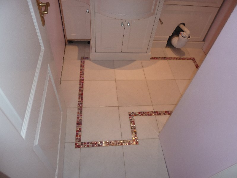 Pink glass mosaics cut into ceramic floor tiles.