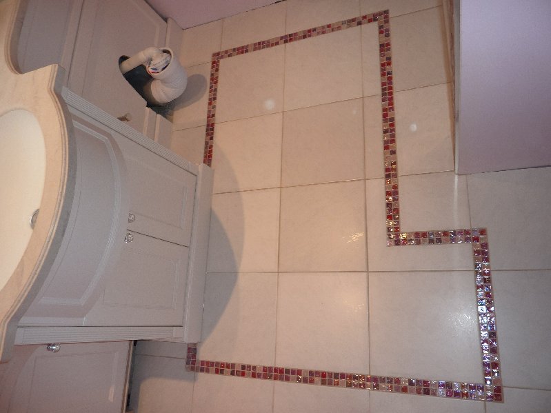 Small ensuit floor tiled in ceramic floor tiles with glass mosaics cut into the tile.