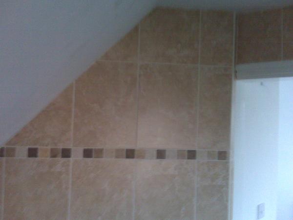 Wall tiling in sloping ceiling, traventine border.